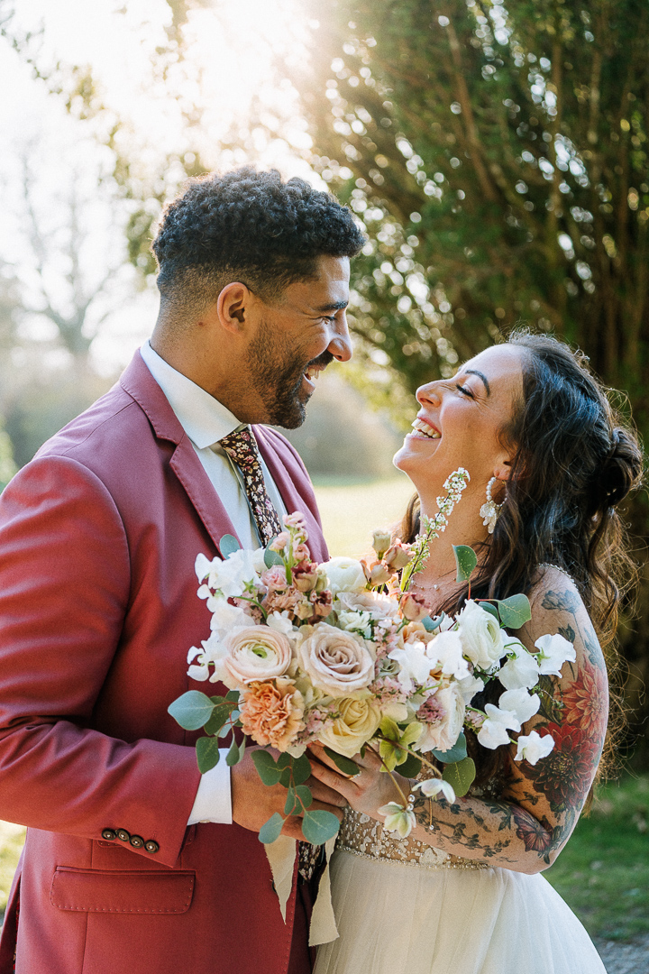 Bride and groom laughing in embrace with spring bouquet at Culdees Castle.