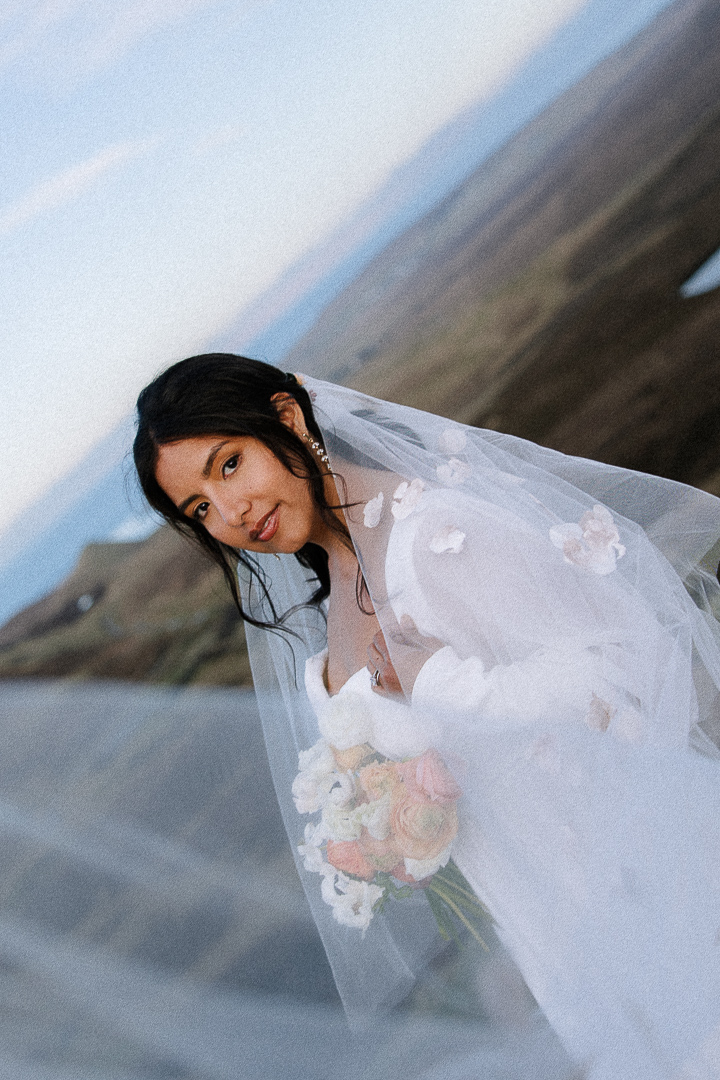 Bride looking directly at camera at an angle, with veil draping in front.