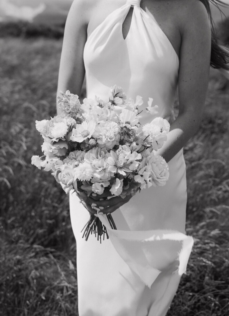 Cropped shot of a bride's dress and bouquet blowing in the wind.