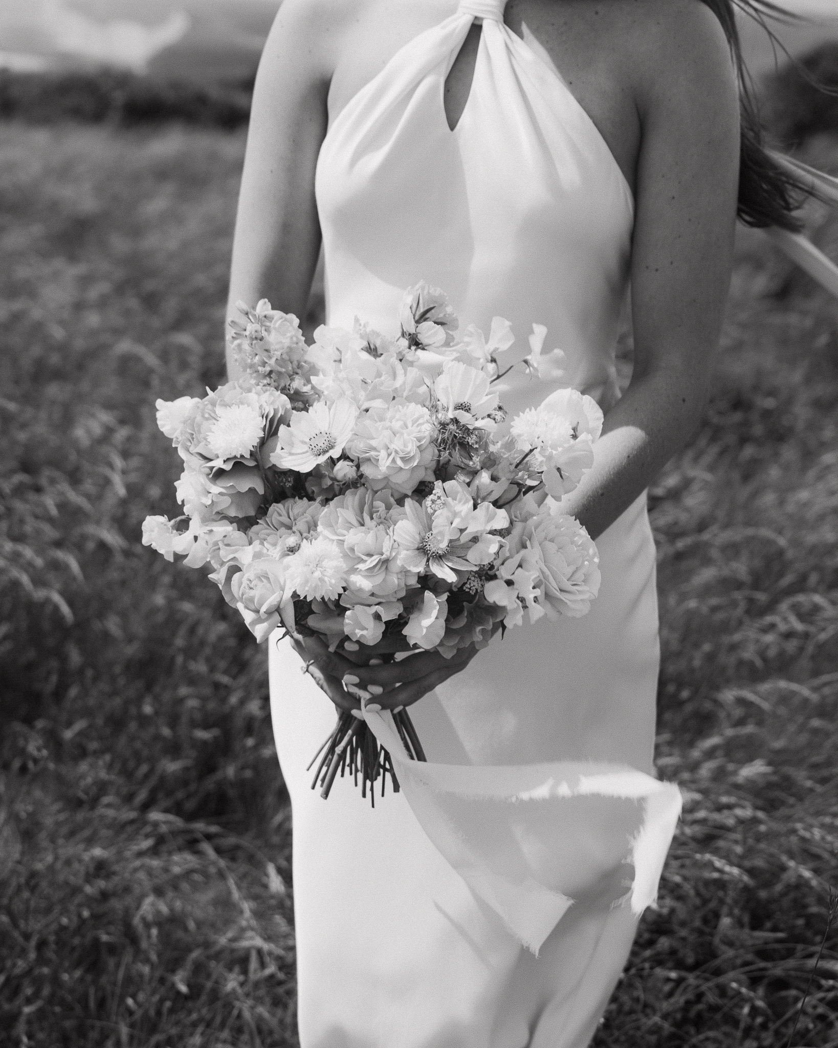 Cropped shot of a bride's dress and bouquet blowing in the wind.