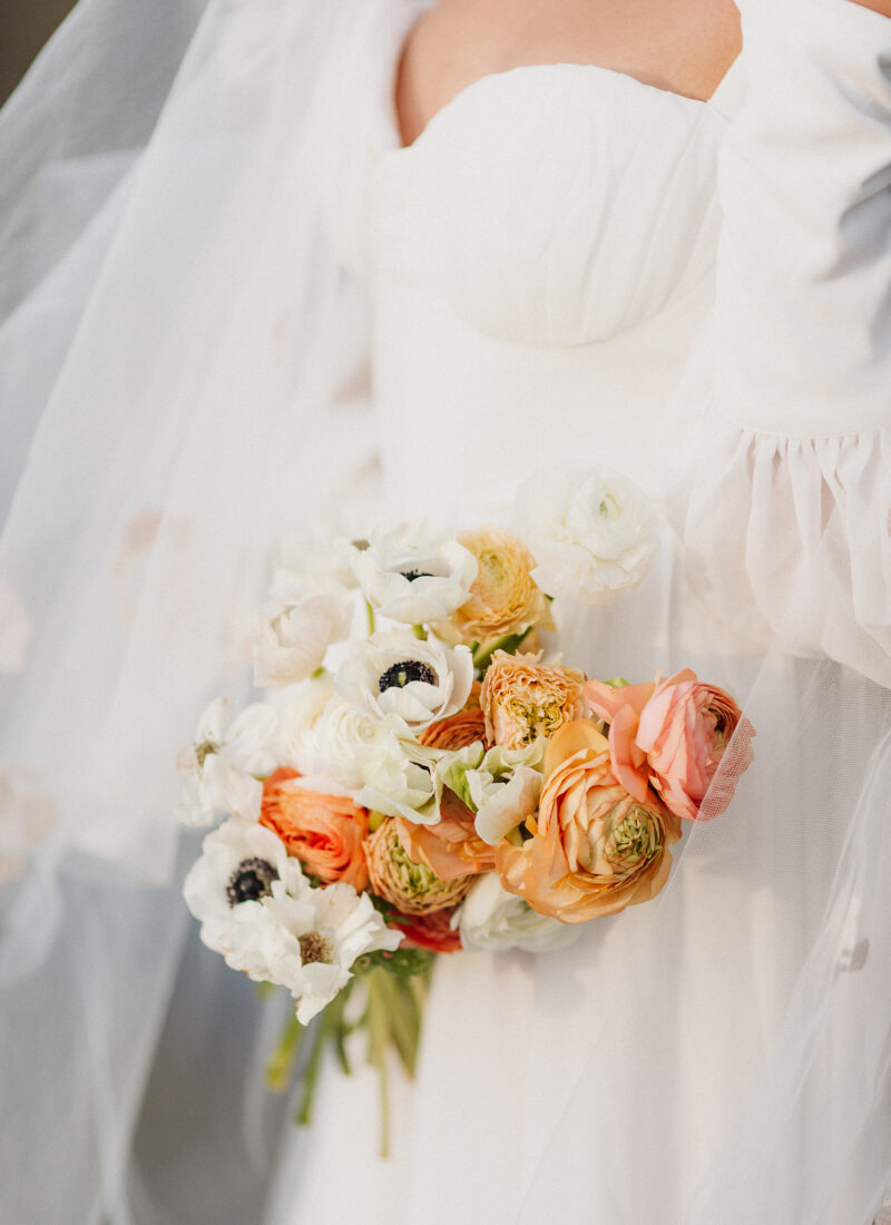 Cropped in shot of a bride holding her colourful spring bouquet.