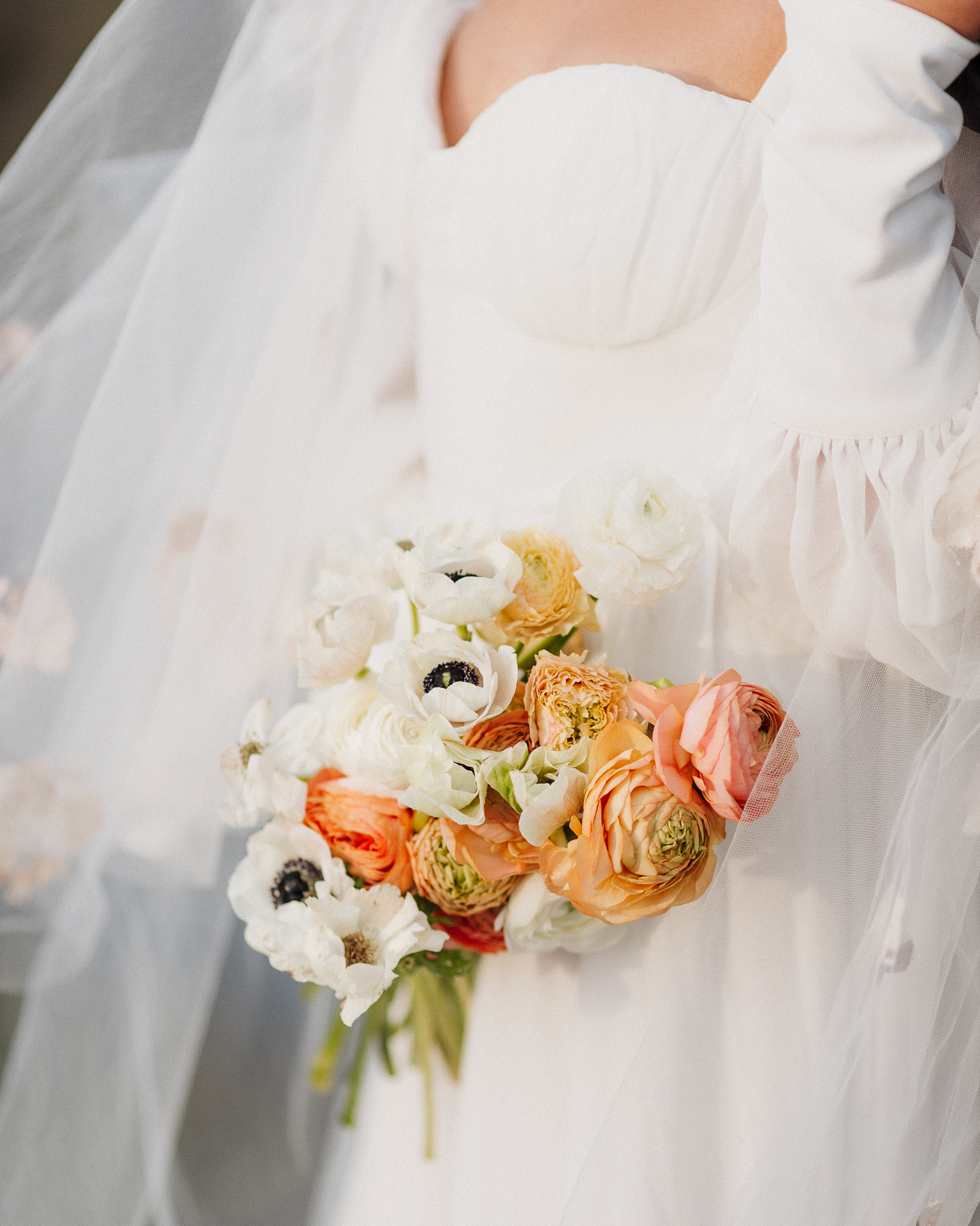 Cropped in shot of a bride holding her colourful spring bouquet.