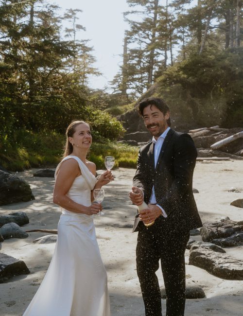 Bride and groom doing a champagne spray on Cox bay Beach in Tofino after elopement.