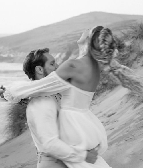 Bride and groom spinning on the beach in cornwall, UK