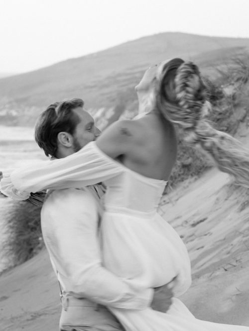 Bride and groom spinning on the beach in cornwall, UK